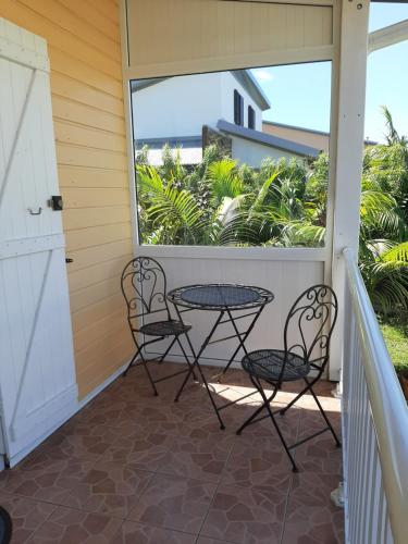 een patio met 2 stoelen en een tafel op een balkon bij Le Palmier in Saint-Philippe