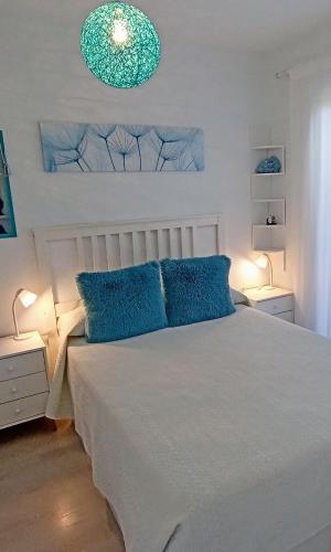 a bedroom with a white bed with blue pillows at Apartamento El Príncipe in Peniscola