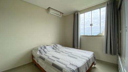 een slaapkamer met een bed voor een raam bij Aconchegante Apartamento na Praia de Bombas com ótima localização. in Bombinhas