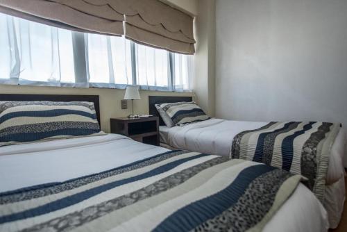two beds in a room with a window at Hotel Capelli Express in Talca