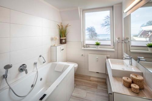 ein weißes Badezimmer mit einer Badewanne und einem Waschbecken in der Unterkunft Dream BIg Strandsuite in Rettin