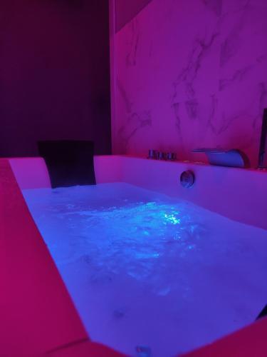 a hot tub in a room with pink and blue lighting at Groom Epernay - Jacuzzi & Champagne in Épernay