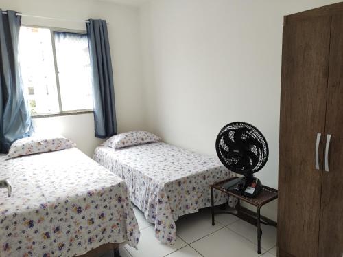 a room with two beds and a table and a window at Apartamento Condominio Caminho dos Ventos in Aracaju
