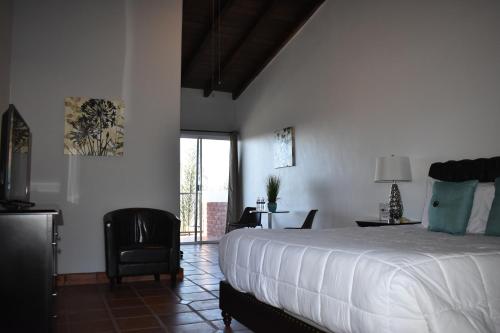 sypialnia z dużym łóżkiem i krzesłem w obiekcie Viñas del Castillo w mieście Ensenada