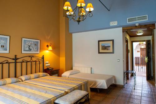 a bedroom with two beds and a chandelier at Huerta de las Palomas in Priego de Córdoba