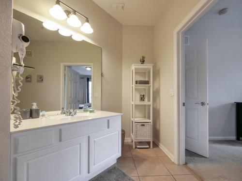 ein Badezimmer mit einem Waschbecken und einem großen Spiegel in der Unterkunft 3Br 2Bath Condo Balcony 5min Conv Center 1388ft in Orlando