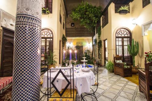 una sala da pranzo con tavolo al centro di un edificio di Riad Letchina a Fes