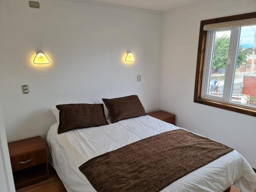 1 dormitorio con 1 cama con 2 almohadas y ventana en Alto Balmaceda, en Puerto Natales