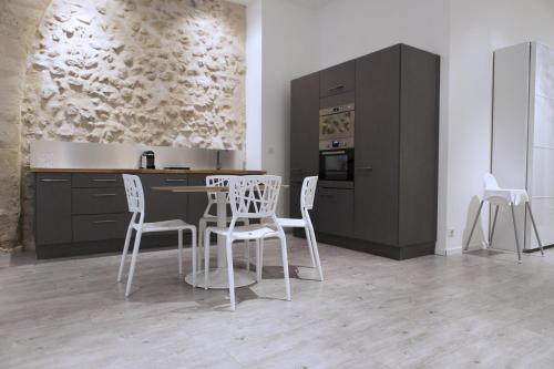 une cuisine avec des chaises blanches, une table et des armoires dans l'établissement Ausone Beautiful loft apartment in historical center + terrace and parking, à Bordeaux