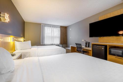 a hotel room with two beds and a flat screen tv at Clarion Pointe Quebec Airport in Quebec City