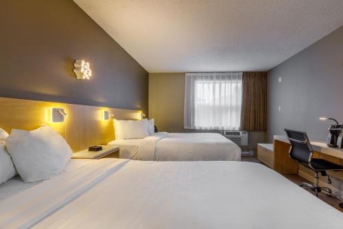 a hotel room with two beds and a desk at Clarion Pointe Quebec Airport in Quebec City