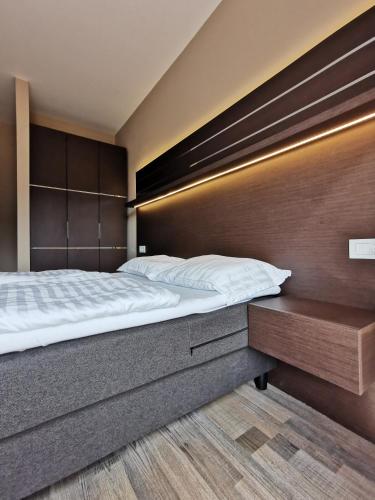 Kopaonik Lux Apartman في كوباونيك: غرفة نوم بسرير كبير و اللوح الأمامي خشبي