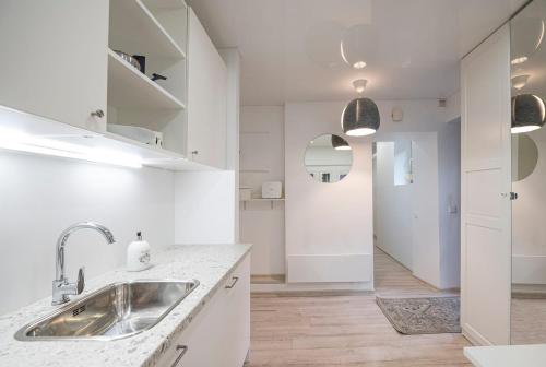 a white kitchen with a sink and a hallway at Kepezinski Centre Apartments in Kaunas