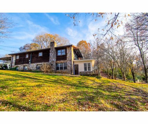 a house on a hill with a grassy field at Classic Lake House Lakefront with Fire Pit and Dock in Louisville