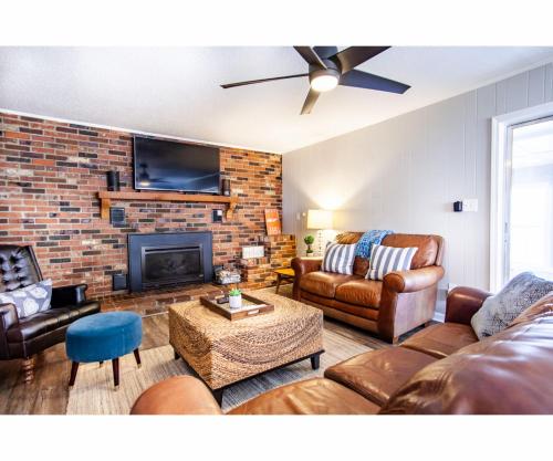 a living room with leather furniture and a brick wall at Classic Lake House Lakefront with Fire Pit and Dock in Louisville