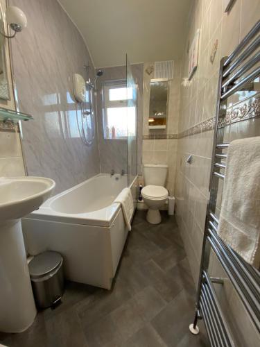 a bathroom with a tub and a toilet and a sink at Spacious Stylish Residence in Leeds