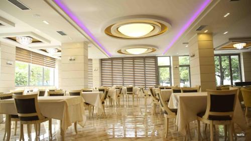 a restaurant with white tables and chairs and purple lighting at Hotel Pogradeci in Pogradec