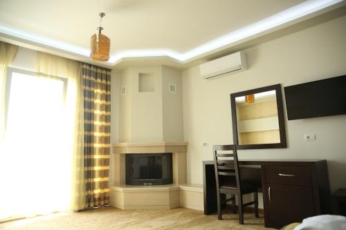 a living room with a television and a table and a mirror at Hotel Pogradeci in Pogradec