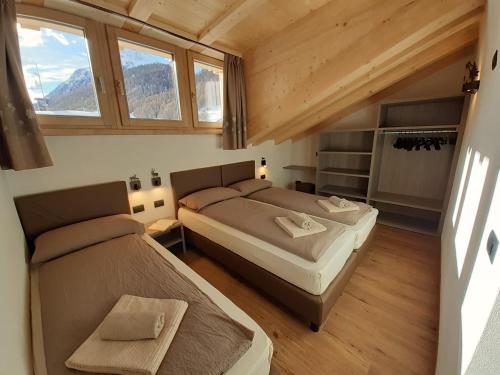 two beds in a small room with windows at Appartamenti Florin in Livigno