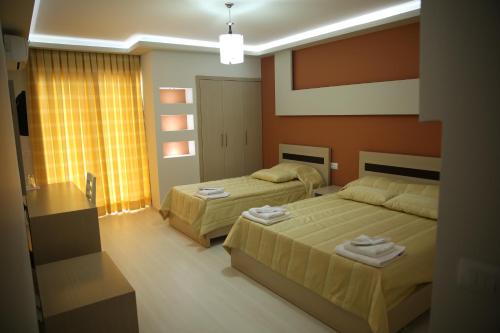 two beds in a bedroom with orange walls at Hotel Pogradeci in Pogradec