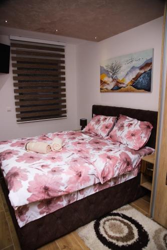 a bedroom with a bed with pink sheets and a window at Avenija in Kragujevac