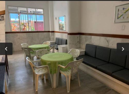 a room with two tables and a couch and chairs at Loft encantador centro Guarapari in Guarapari