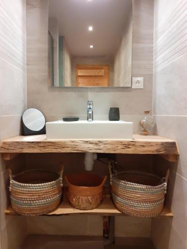 uma casa de banho com um lavatório e cestos numa prateleira em Appartement chaleureux avec wifi de 10 personnes à Val-Cenis em Lanslebourg-Mont-Cenis