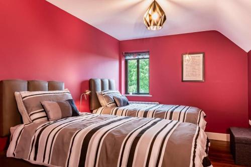two beds in a room with red walls at Luxury Country House on the Hill in Kenmare