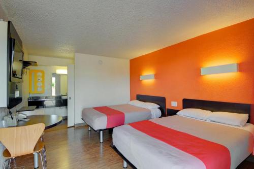 a hotel room with two beds and an orange wall at Economy Hotel Plus in Oklahoma City