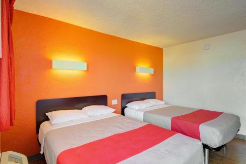 Economy Hotel Plus في مدينة اوكلاهوما: سريرين في غرفة الفندق بجدران برتقالية