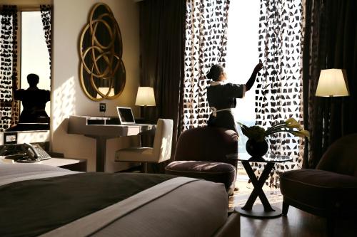 a woman standing in a hotel room looking out the window at Lancaster Plaza Beirut in Beirut