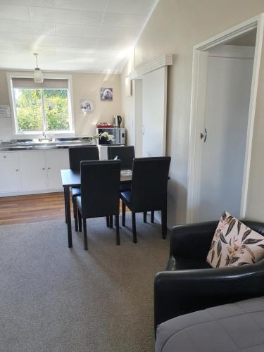 a living room with a table and chairs and a kitchen at Gardner Court Motel in Napier