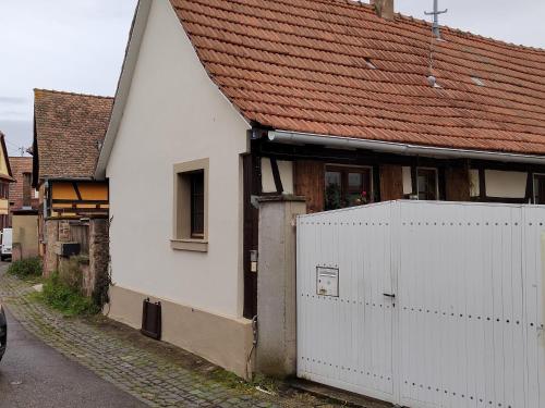a white house with a red roof and a white fence at Petite maison alsacienne in Entzheim
