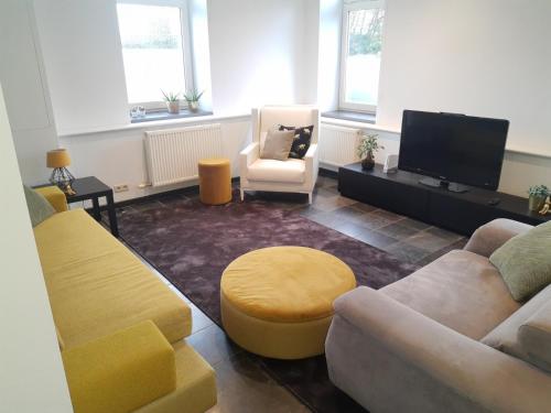 a living room with couches and a flat screen tv at Vakantiewoning 'De Vlaamse Aap' in Dilsen-Stokkem