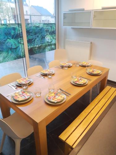 a wooden table with plates and wine glasses on it at Vakantiewoning 'De Vlaamse Aap' in Dilsen-Stokkem