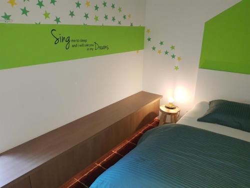 a bedroom with a bed with a green sign on the wall at Vakantiewoning 'De Vlaamse Aap' in Dilsen-Stokkem