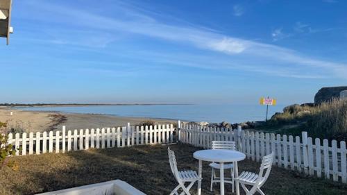- une table et des chaises à côté d'une clôture et de la plage dans l'établissement MAISON SUR LA PLAGE avec VUE MER PANORAMIQUE, à Le Martray