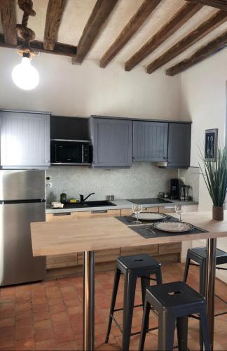 - une cuisine avec une table et quelques tabourets dans l'établissement Les pieds dans l'eau TROPICANA, à Corné