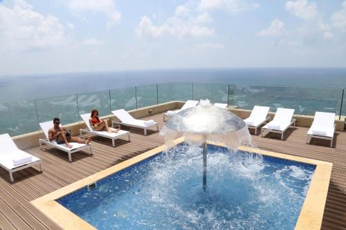 two women sitting on a deck next to a swimming pool at Lancaster Plaza Beirut in Beirut