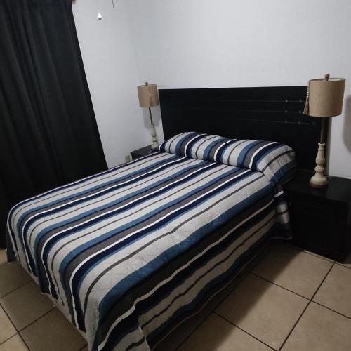 a bed with a blue and white striped blanket on it at Casa Villa Serena 21 in San Carlos