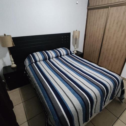 a bed with a blue and white striped blanket on it at Casa Villa Serena 21 in San Carlos