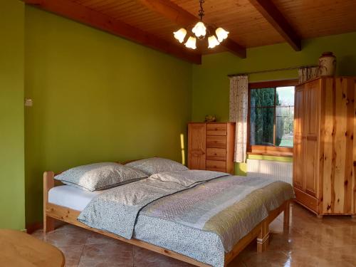 Dormitorio verde con cama y ventana en Agroturystyka Tam Gdzie Sosny, en Ścinawka Dolna