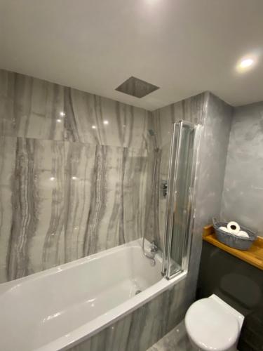 a bathroom with a bath tub and a toilet at Hollemeadow in Bloxwich