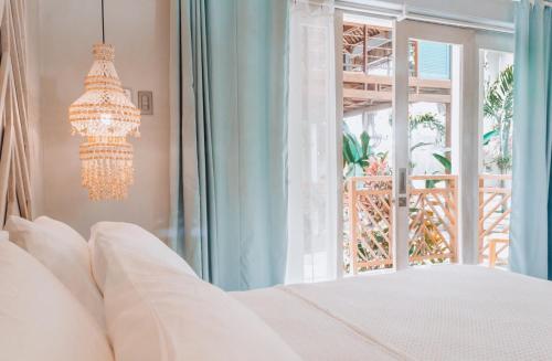 a bedroom with a bed and a chandelier and a window at MUNI MUNI VILLAS SIARGAO in General Luna