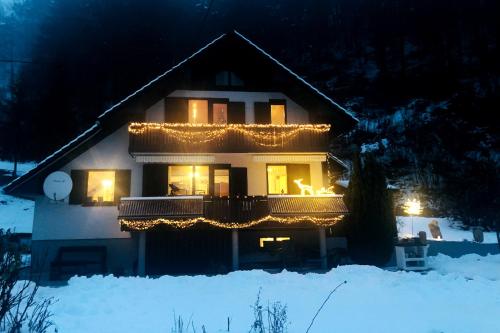 a house decorated with christmas lights in the snow at SavaDolinka House in Mojstrana