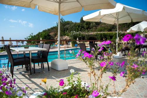 a patio with tables and umbrellas and a pool at Karavados Beach Hotel in Karavadhos
