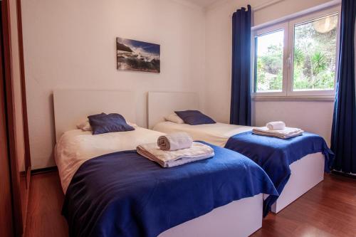 a bedroom with two beds with blue sheets and a window at Ocean, Pines and Mountain in Sintra
