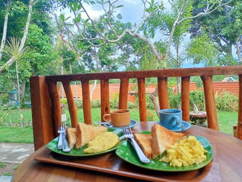 a table with two plates of toast and scrambled eggs at Grealeen Cottages in Nusa Penida