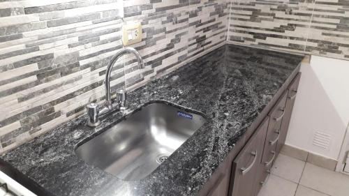 a stainless steel sink in a kitchen with a brick wall at Casa Necochea in Necochea