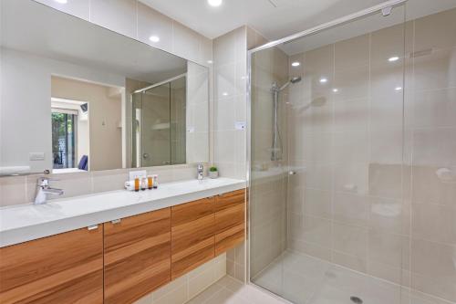 a bathroom with a shower and a sink and a mirror at Coco Mooloolaba in Mooloolaba